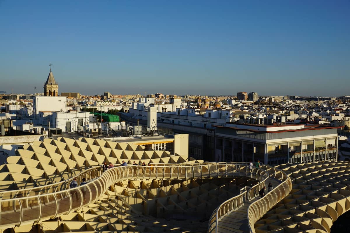 มุมมองไวด์แองเกิลจากด้านบนของแพลตฟอร์ม Metropol Parasol พร้อมวิวเมือง Seville ที่ทอดยาวใต้ท้องฟ้าสีฟ้าใส