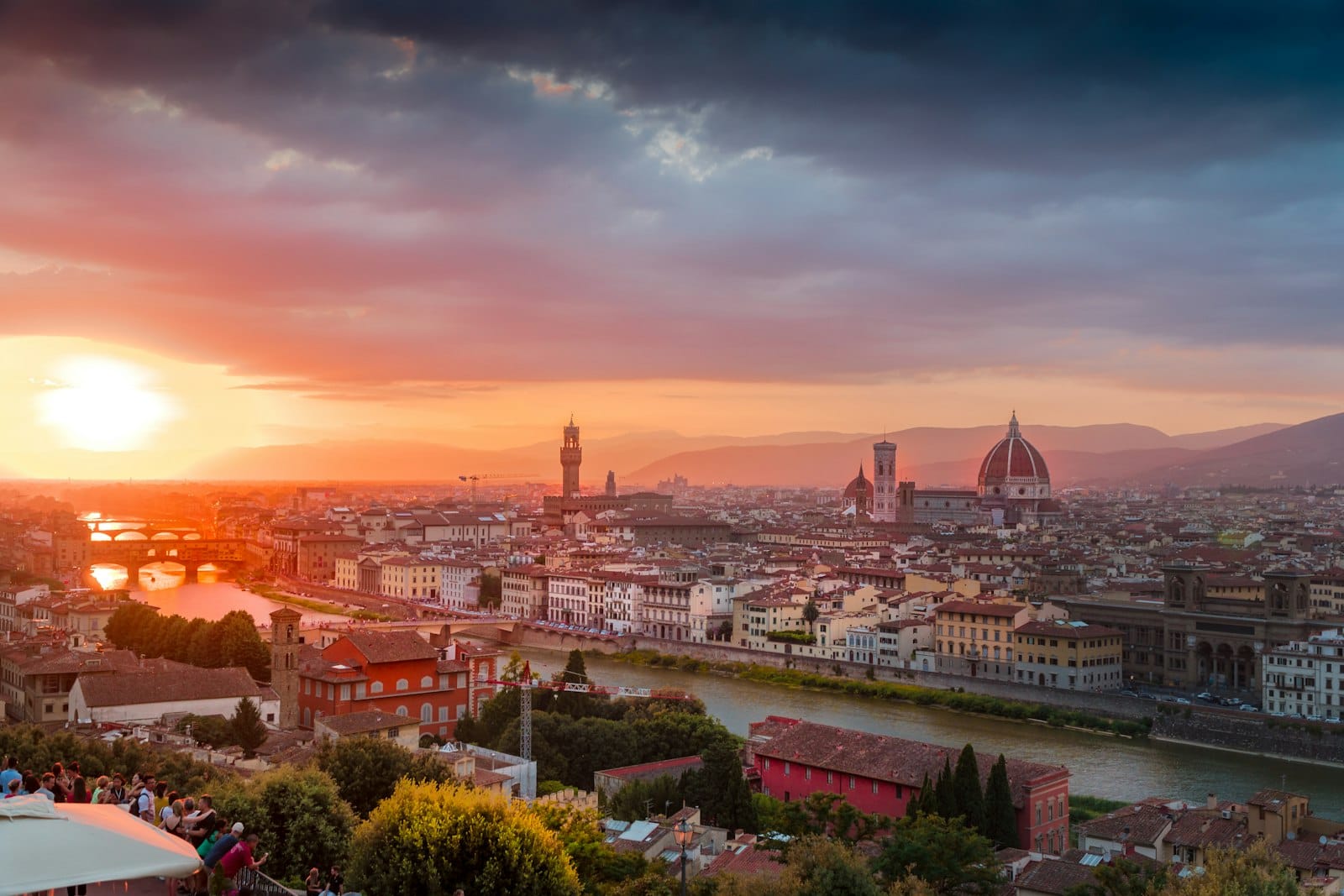 เส้นขอบฟ้าของ Florence ยามพระอาทิตย์ตกดินจากจุดชมวิวบนเนินเขา โดยมีแม่น้ำ Arno, Duomo และอาคารประวัติศาสตร์ให้เห็นใต้เมฆที่สวยงามตระการตา