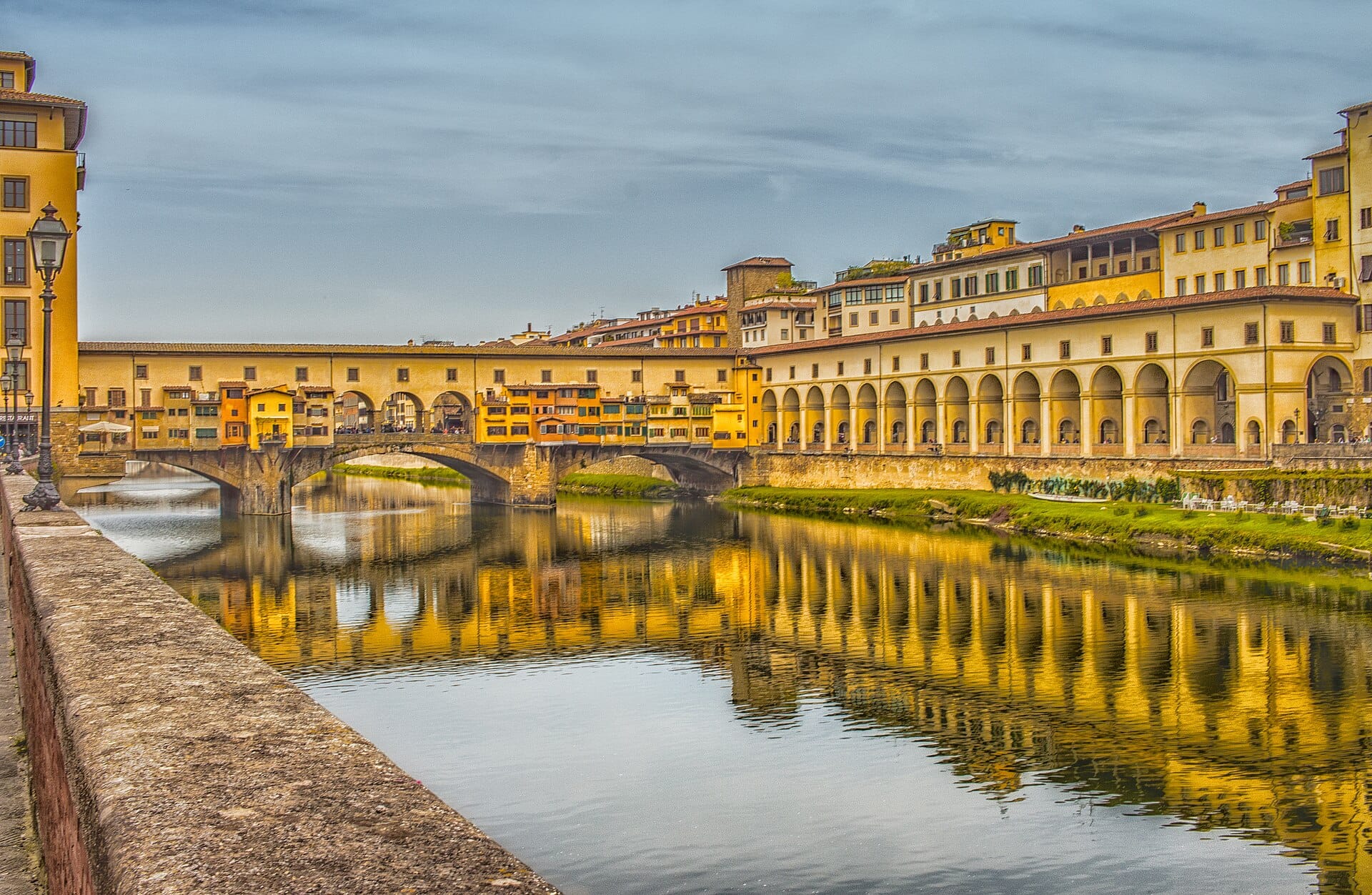 วิวของ Ponte Vecchio และอาคารริมแม่น้ำในฟลอเรนซ์ที่สะท้อนบนผิวน้ำอันสงบของแม่น้ำ Arno ในระดับสายตา