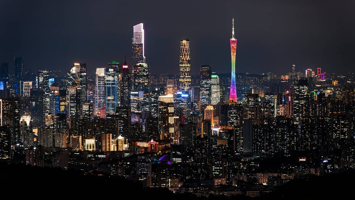 Nighttime cityscape of Guangzhou with illuminated Canton Tower and modern skyscrapers viewed from a high vantage point.