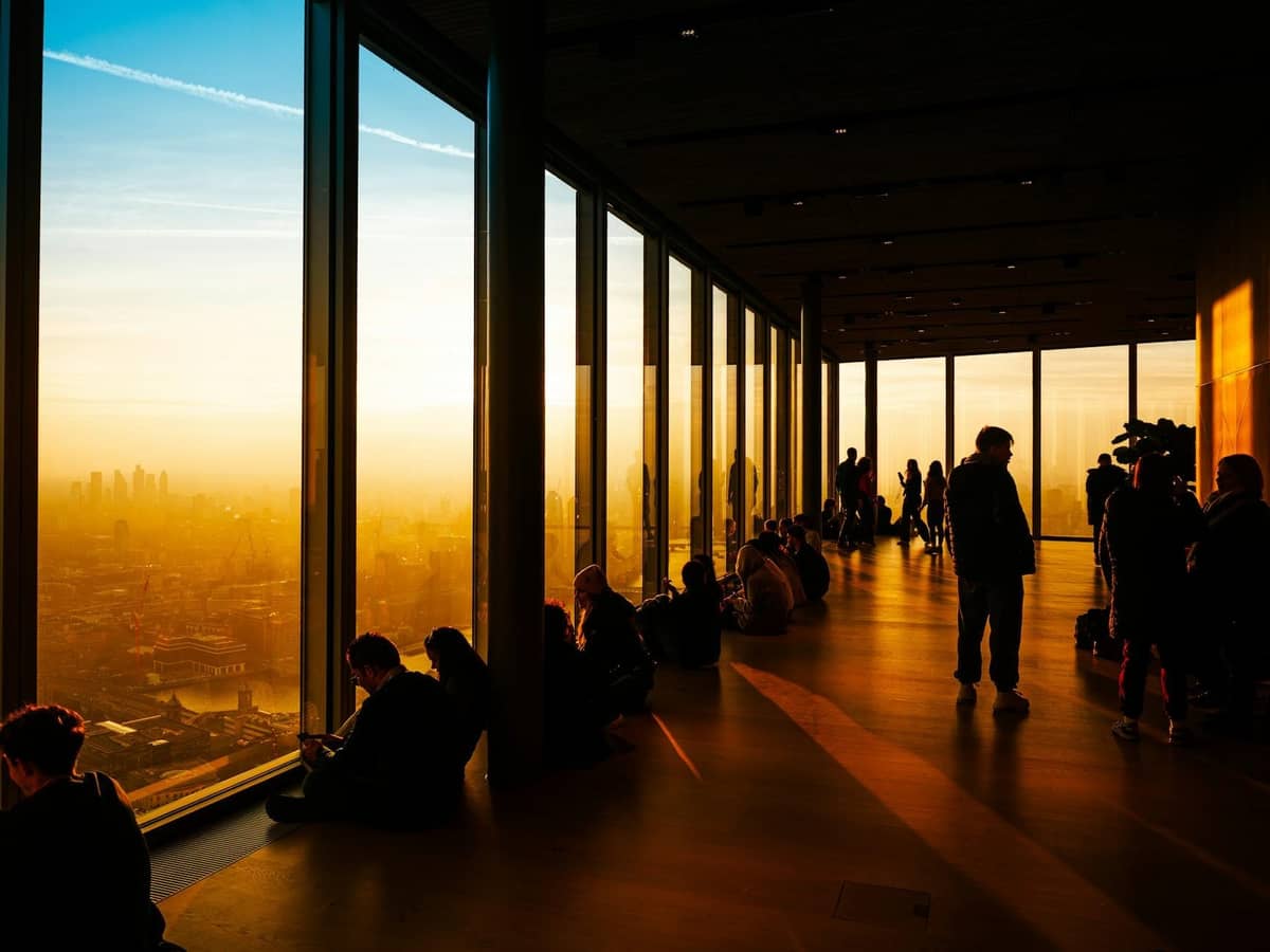 Pessoas aproveitando o pôr do sol em um moderno deck de observação de vidro com vistas panorâmicas de London.
