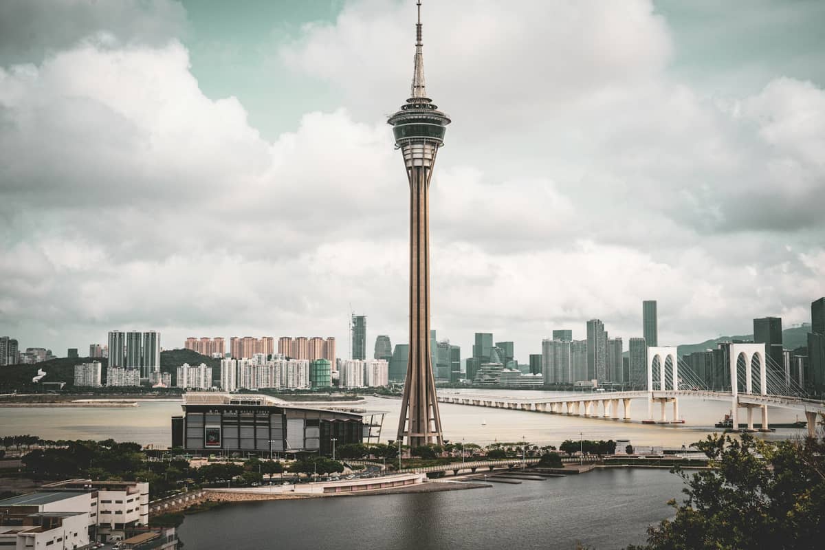 Macau Tower und Sai Van Bridge vom Ufer aus gesehen mit der Skyline der Stadt und Wasser im Vordergrund bei Tag