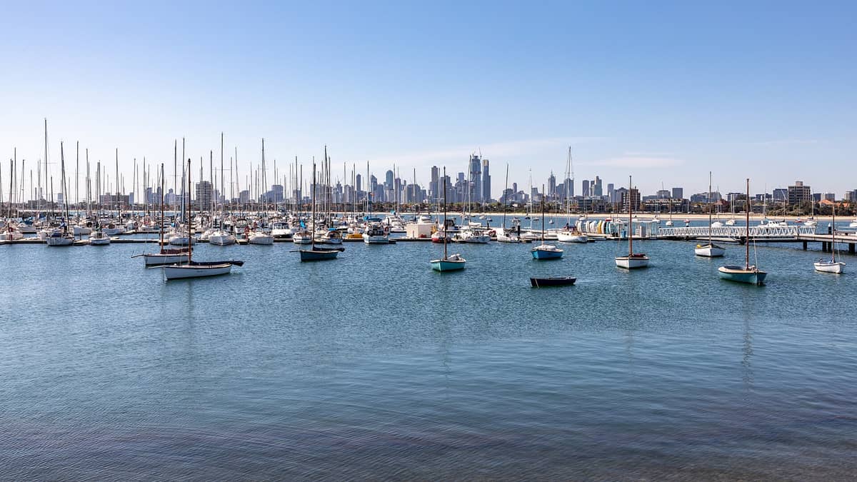 Szeroki dzienny widok na panoramę Melbourne z mariny St Kilda z wieloma żaglówkami w zatoce i błękitnym niebem.