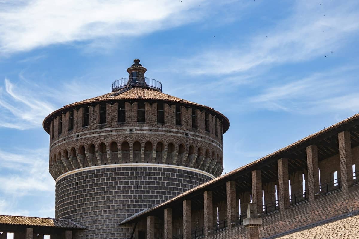 Zbliżenie na Torre del Filarete w Castello Sforzesco w Mediolanie pod jasnym błękitnym niebem z delikatnymi chmurami.