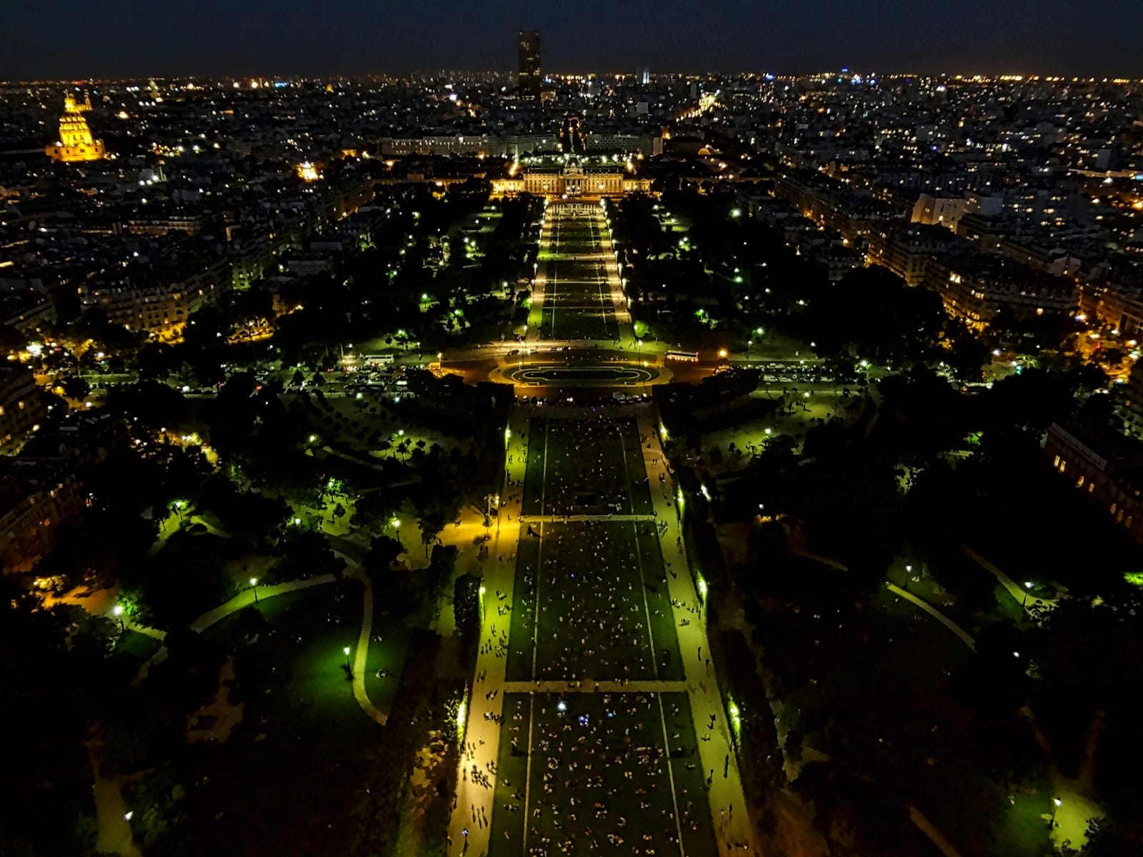 Nächtliche Luftaufnahme von Paris mit Gärten und Stadtlichtern, von oben aufgenommen, mit einem klassischen Pariser Stadtbild.