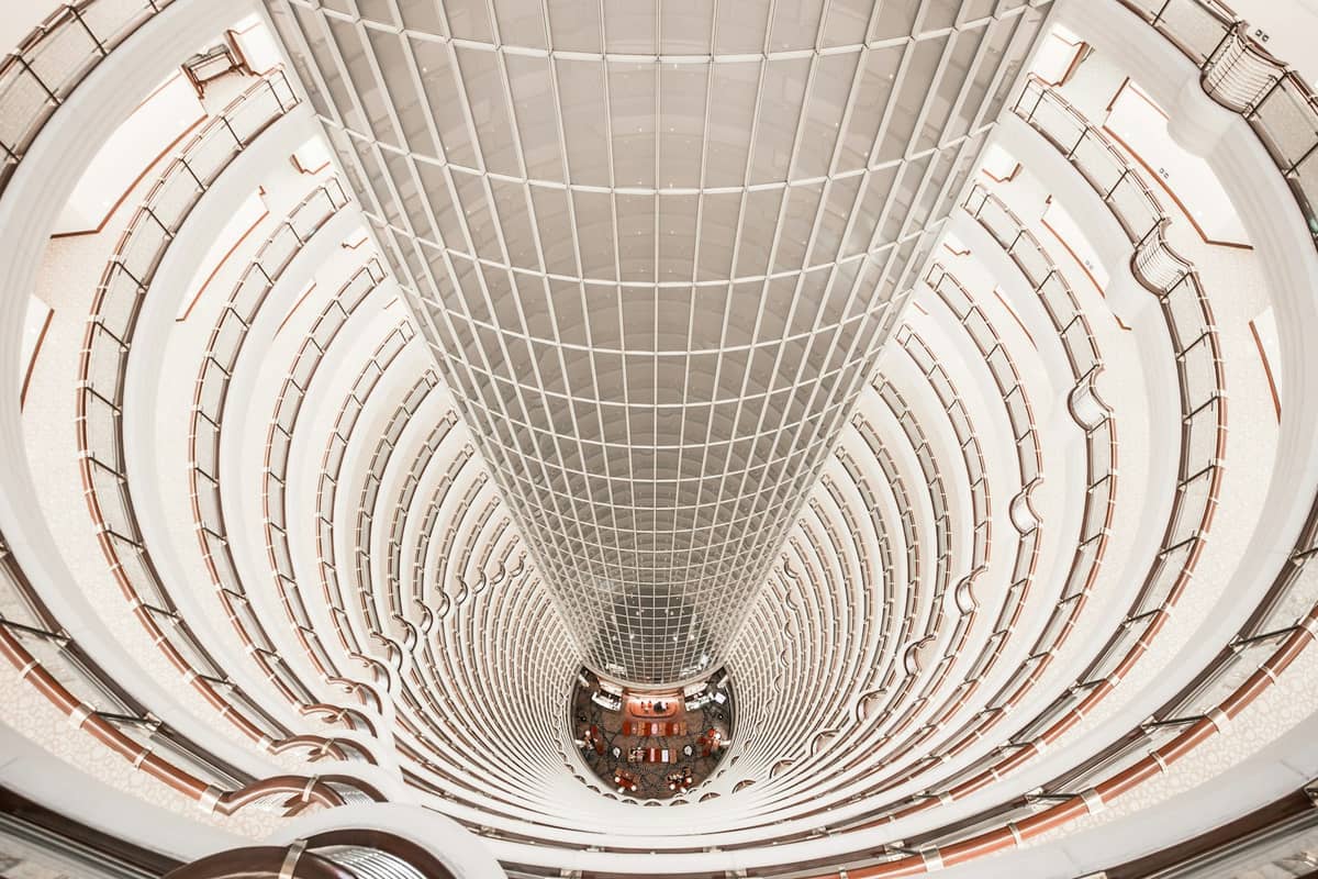 Pemandangan dramatis yang memandang ke bawah ke dalam atrium silindris Jin Mao Tower yang menjulang tinggi, memperlihatkan arsitektur bertingkat tinggi khas Shanghai.