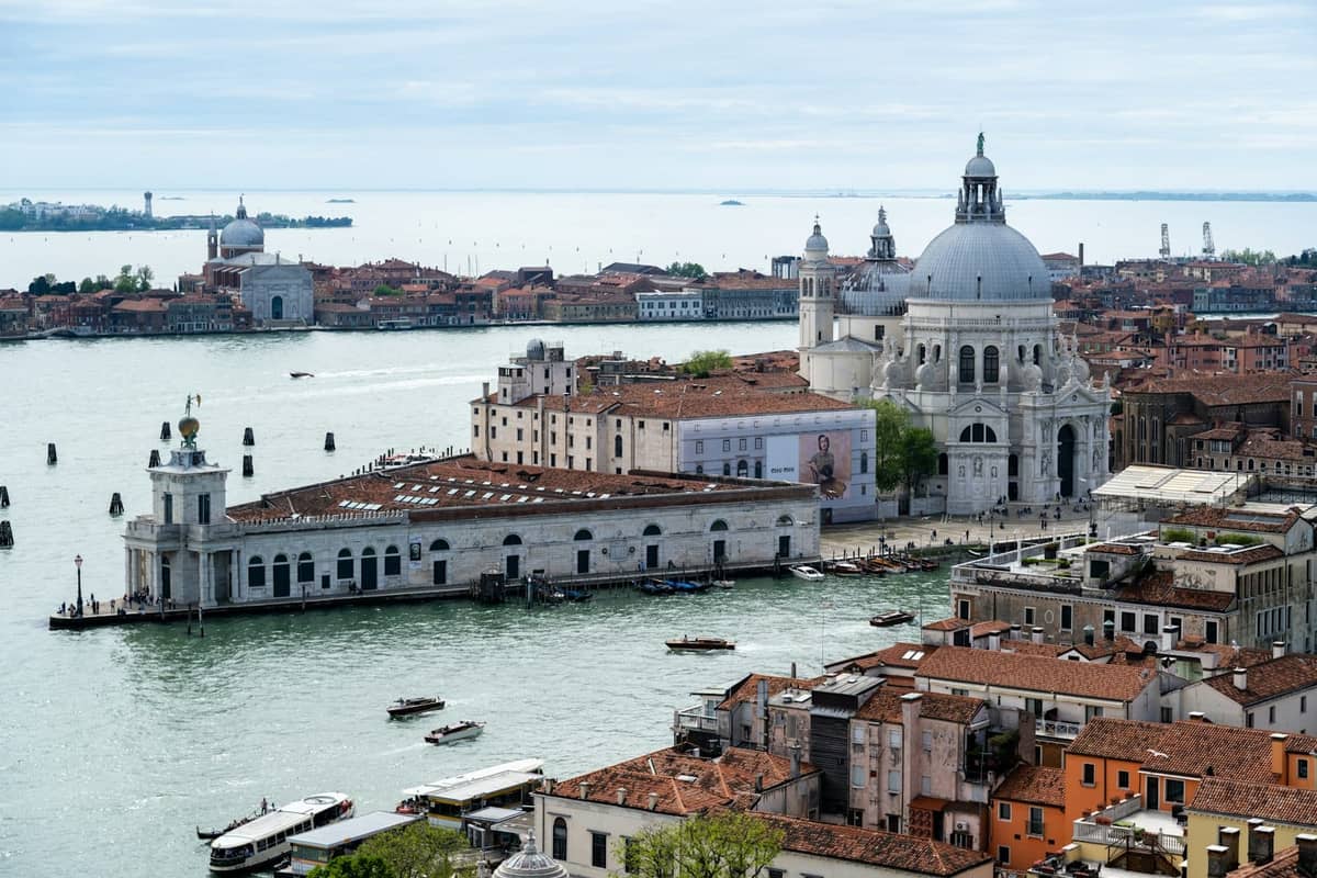 Luftaufnahme von Venedig mit dem Canal Grande, der Basilica di Santa Maria della Salute und den umliegenden Dächern, aufgenommen aus der Perspektive eines hohen Turms.