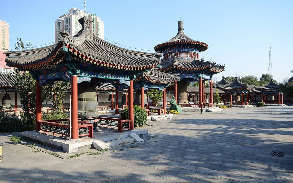 Traditionelle chinesische Pavillonbauten und riesige Bronzeglocken am Big Bell Temple in Peking an einem klaren, sonnigen Tag.
