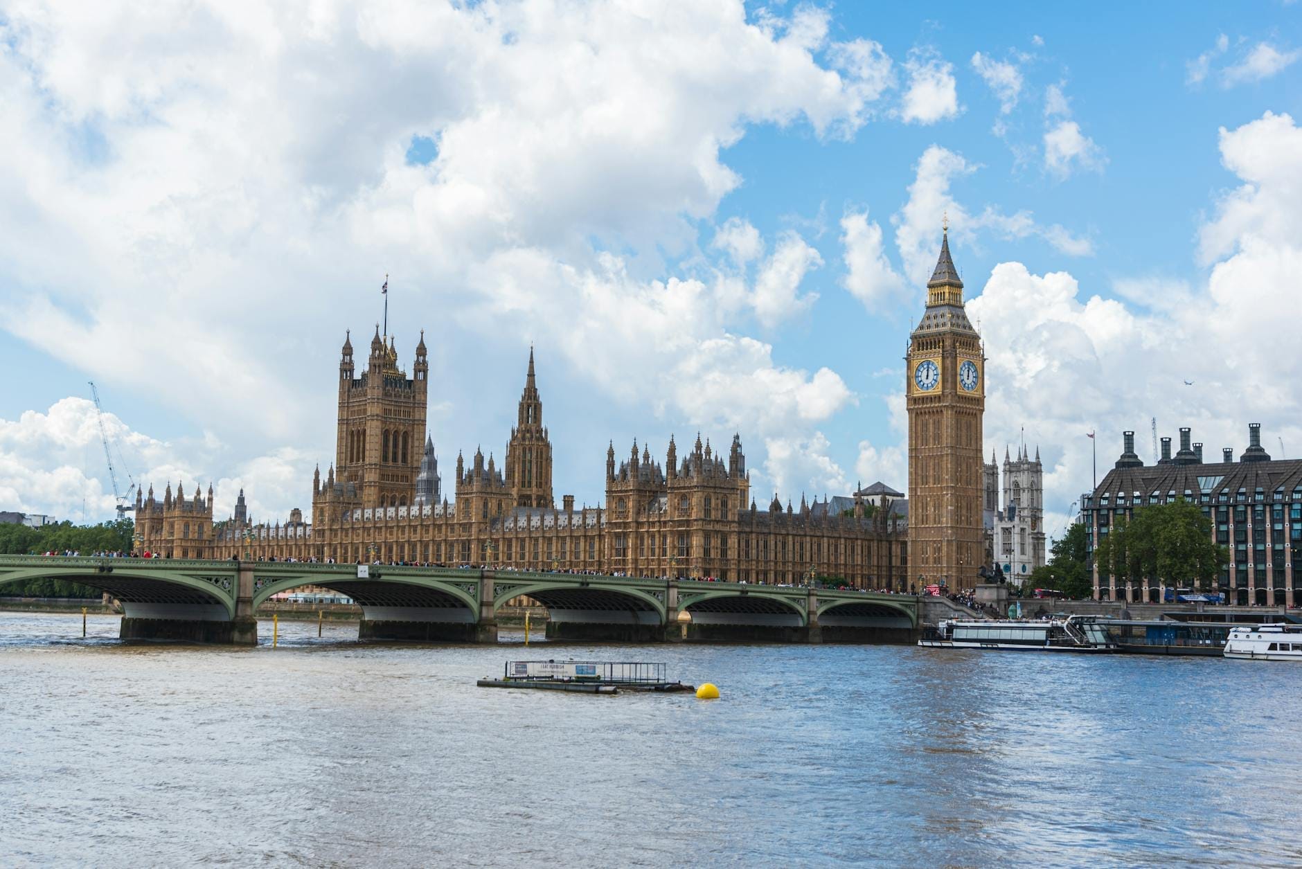 Big Ben e il Parlamento a Londra con il Westminster Bridge sul Tamigi in una giornata luminosa e parzialmente nuvolosa.
