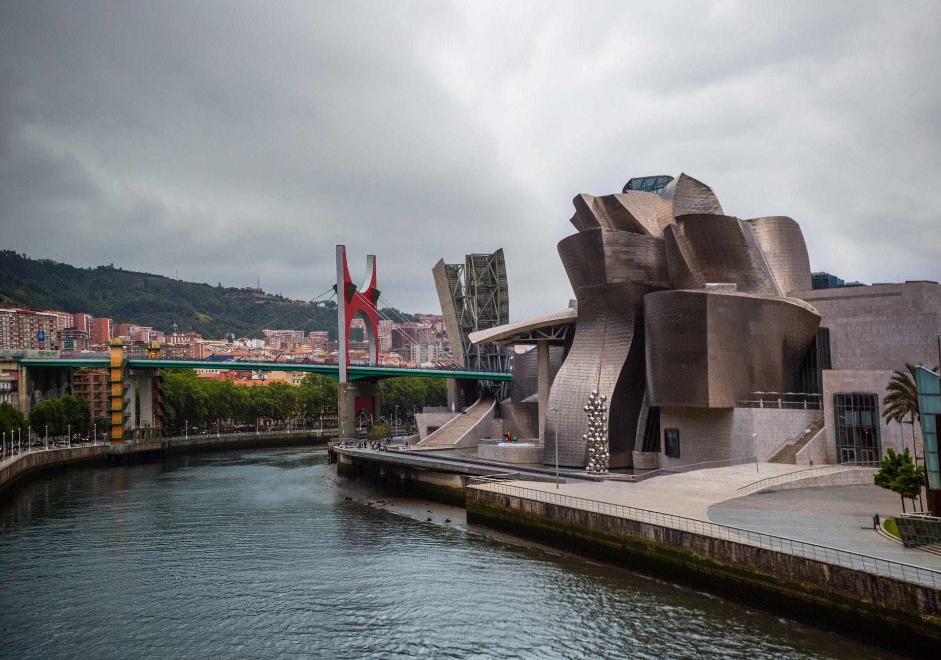 วันฤดูหนาวที่มีเมฆมากที่พิพิธภัณฑ์ Guggenheim และสะพาน La Salve ริมแม่น้ำ Nervión เมือง Bilbao ถนนเปียกชื้นและท้องฟ้าครึ้ม