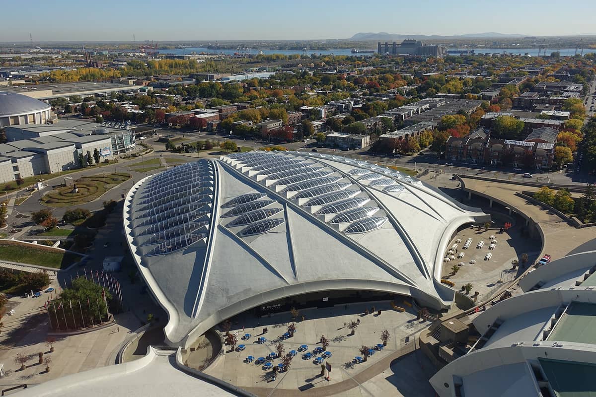 Luftaufnahme des markanten Kuppelbaus des Montrealer Biodômes mit blattförmigen Oberlichtern, umgeben von der Stadtlandschaft und herbstlichen Bäumen im Hintergrund.