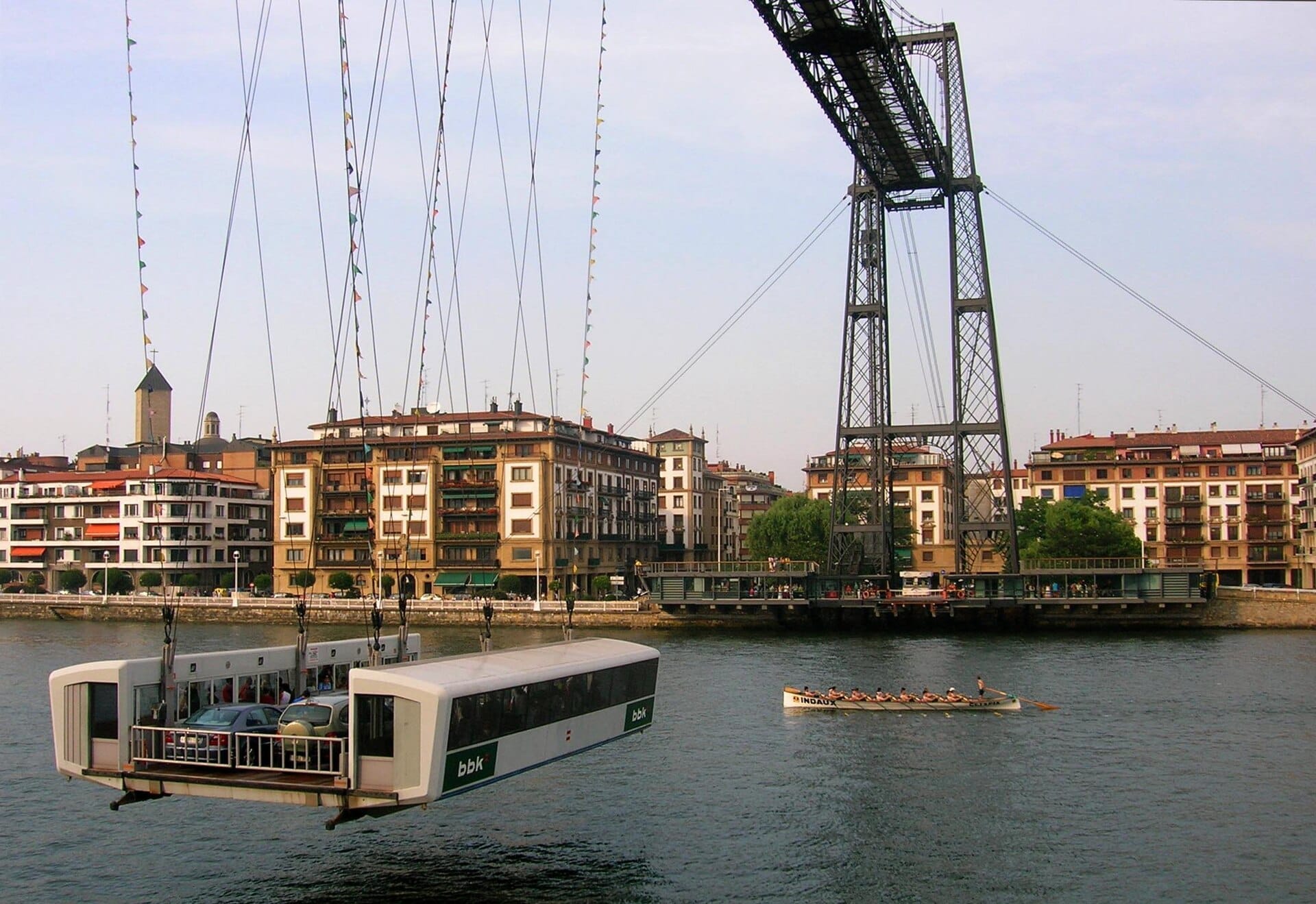 Die Transportgondel der Bizkaia-Brücke befördert Autos und Passagiere über die Nervión-Mündung, mit Flussufer-Apartments und Gebäuden im Hintergrund.