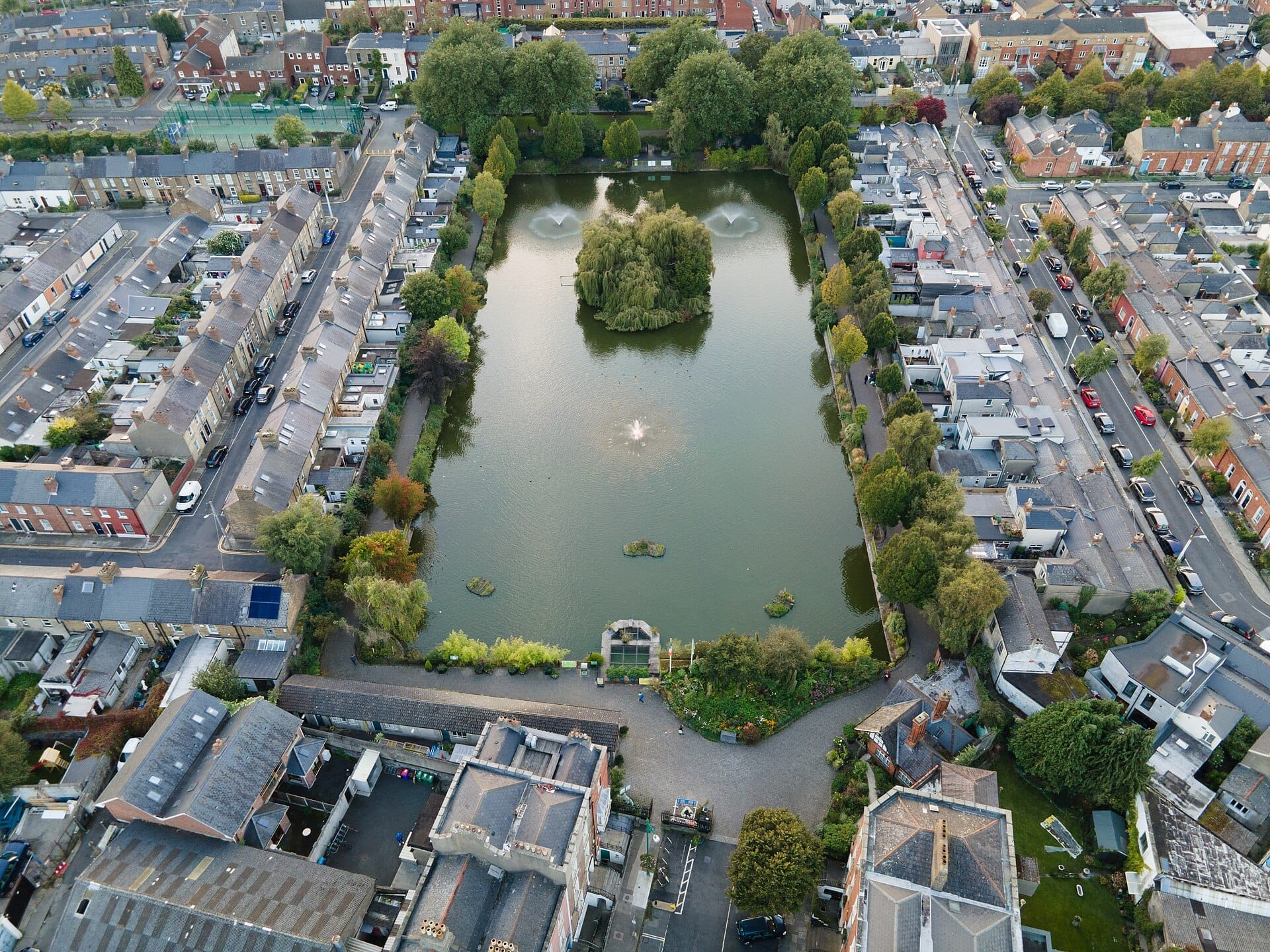 Vista aerea del Blessington Street Basin a Dublino, con il lago centrale, le fontane, i vialetti alberati e le strade residenziali circostanti.