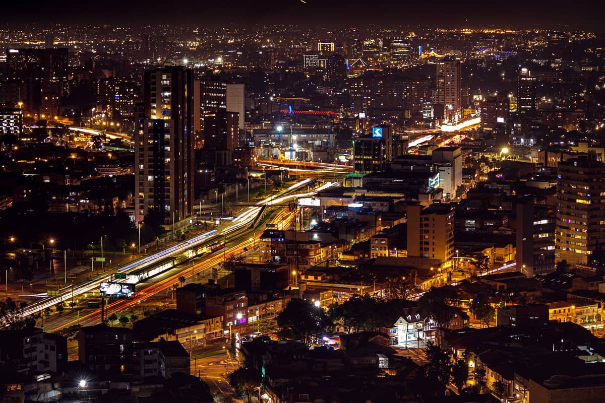 Nighttime aerial view of Bogotá with city lights illuminating major roads and buildings, evoking the festive atmosphere typical of December in the city.