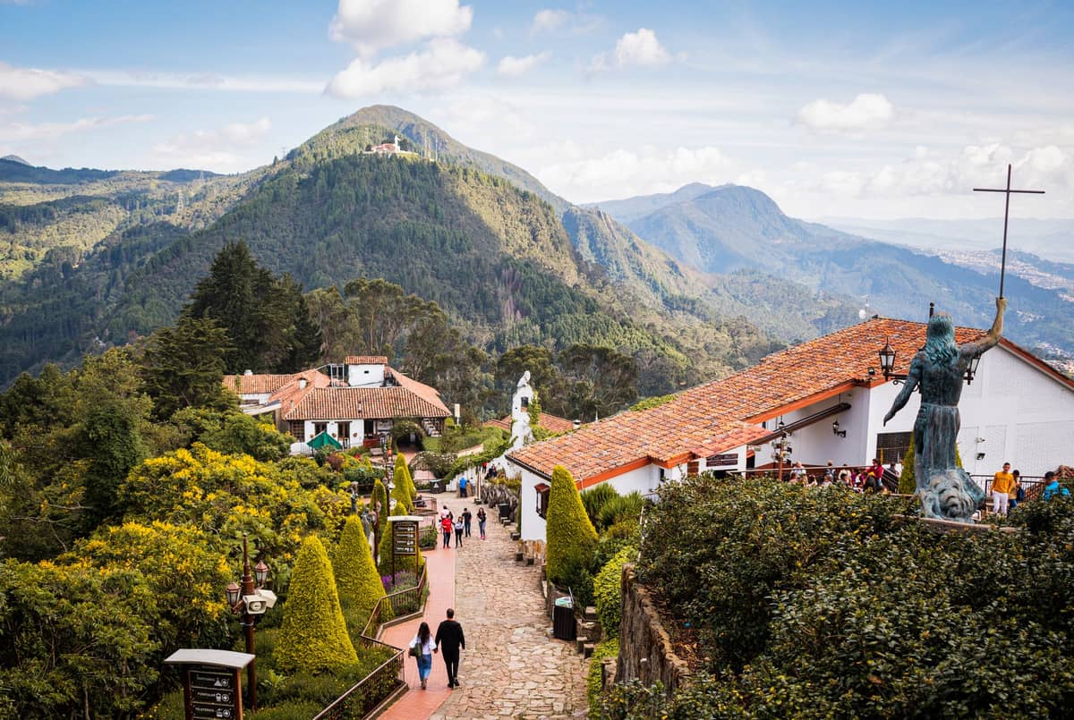 View from Monserrate in Bogotá showing people walking at altitude among mountain scenery and city rooftops