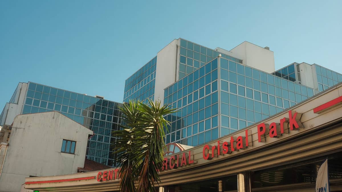 Modern glass office and commercial buildings with signage 'Centro Comercial Cristal Park' under a clear blue sky in Bogotá.