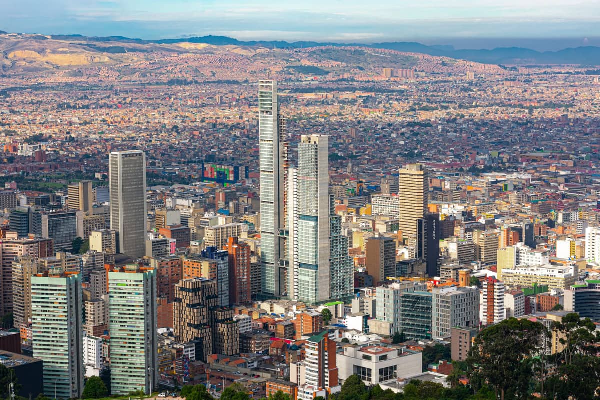 Wide view of Bogotá's city center with tall modern skyscrapers, dense urban landscape, and mountains in the background under a clear sky
