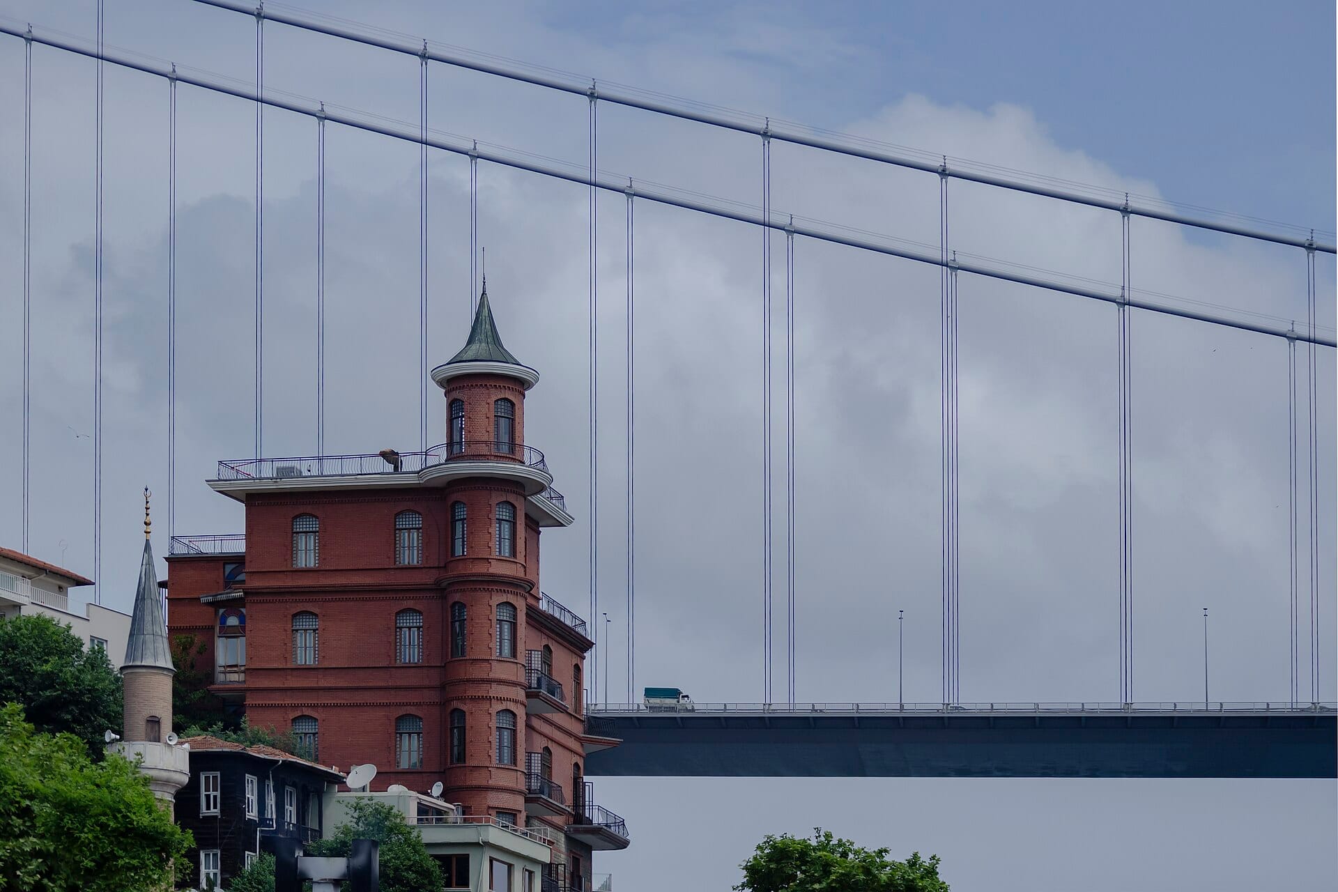 Lo storico Perili Köşk in mattoni rossi, sede del Borusan Contemporary, si erge sotto il Ponte del Bosforo contro un cielo nuvoloso di Istanbul.