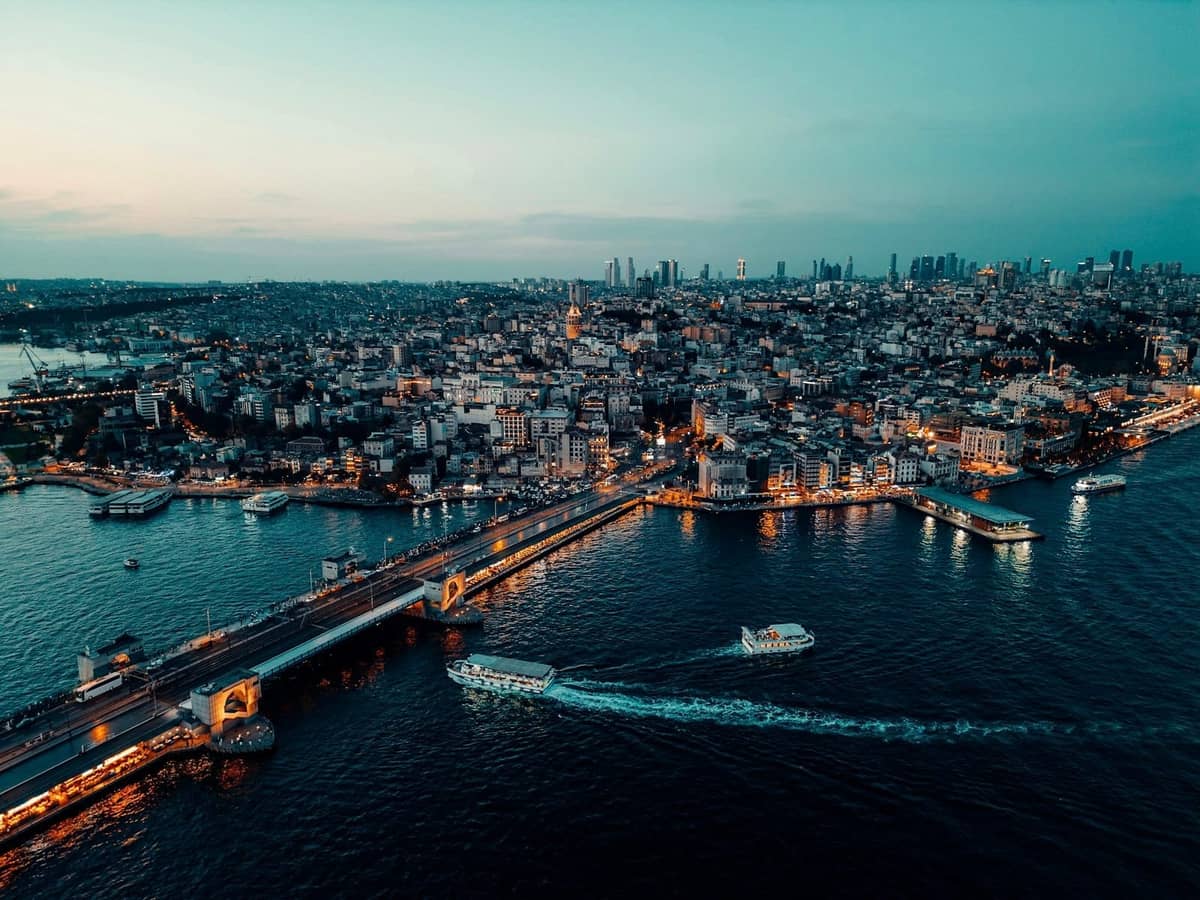 Widok z lotu ptaka na Stambuł z łodziami płynącymi po Bosforze w pobliżu Mostu Galata, panorama miasta i nadwodne zabytki o zmierzchu.