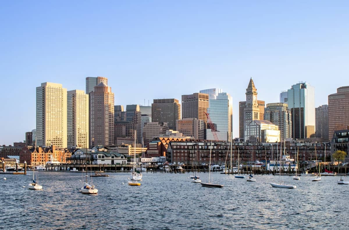 Skyline von Boston mit Segelbooten im Hafen an einem klaren Tag, der Aktivitäten am Wasser und urbane Erkundungen veranschaulicht.
