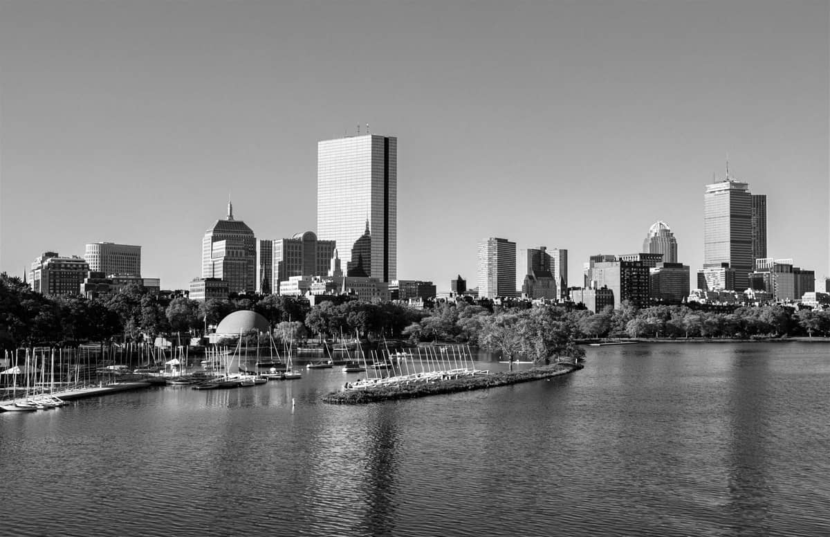 Schwarz-Weiß-Foto der Skyline von Boston über den Charles River, mit dem Esplanade Hatch Shell und Segelbooten.