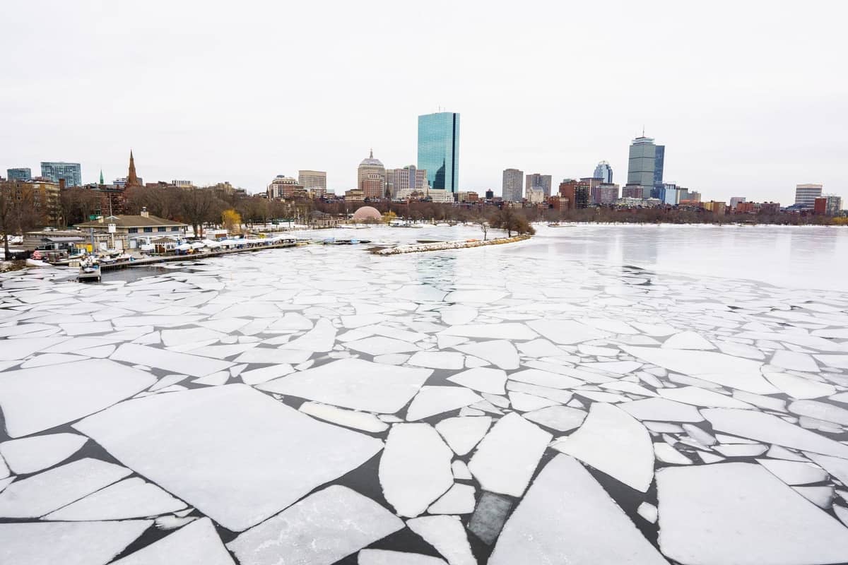 Grandes trozos de hielo roto cubriendo el río Charles congelado con el horizonte de Boston al fondo en un gris día de invierno.