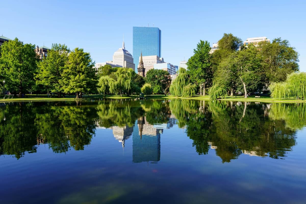 Laguna del Boston Public Garden con el horizonte de la ciudad y el Hancock Tower reflejados en el agua en un día claro y soleado.