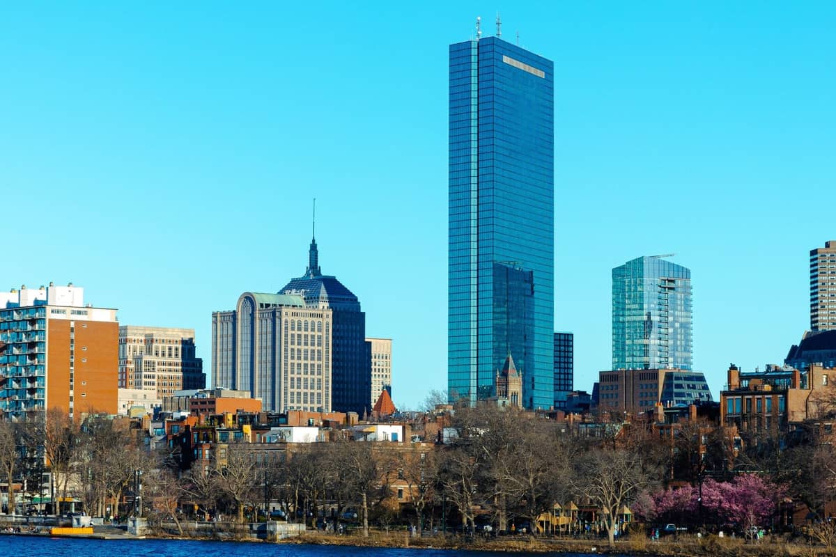 Heller, klarer Blick auf die Skyline von Boston mit markanten Wolkenkratzern und kahlen Bäumen entlang des Charles River an einem frischen Tag.