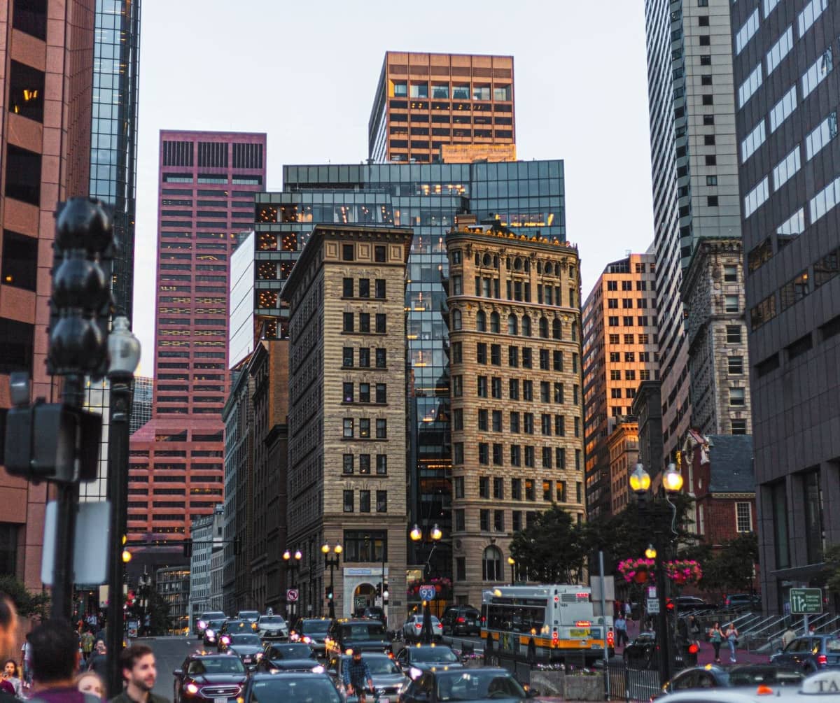 Scène de rue animée de Boston avec des bâtiments historiques et modernes, de la circulation, des piétons et des réverbères caractéristiques au crépuscule dans le centre-ville.
