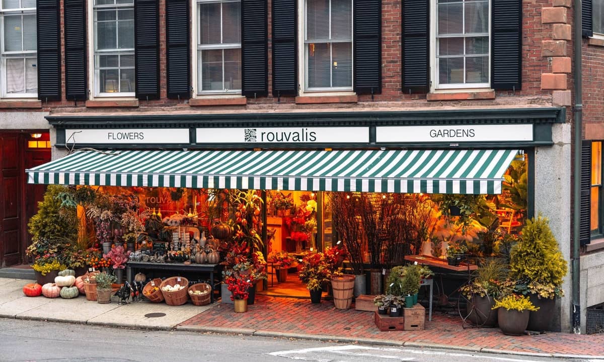 Charmante boutique de fleurs avec auvent rayé vert et jardinières sur la Charles Street pavée de briques à Beacon Hill, Boston.