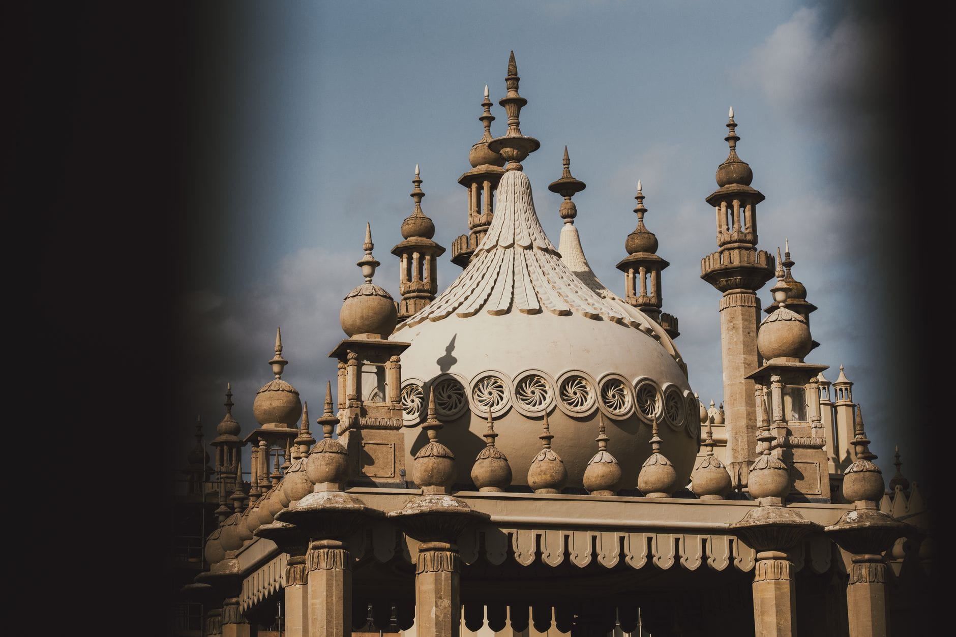 Detailed close-up of the ornate domed roof and minarets of Brighton Dome, highlighting its distinctive architectural features against a light blue sky.