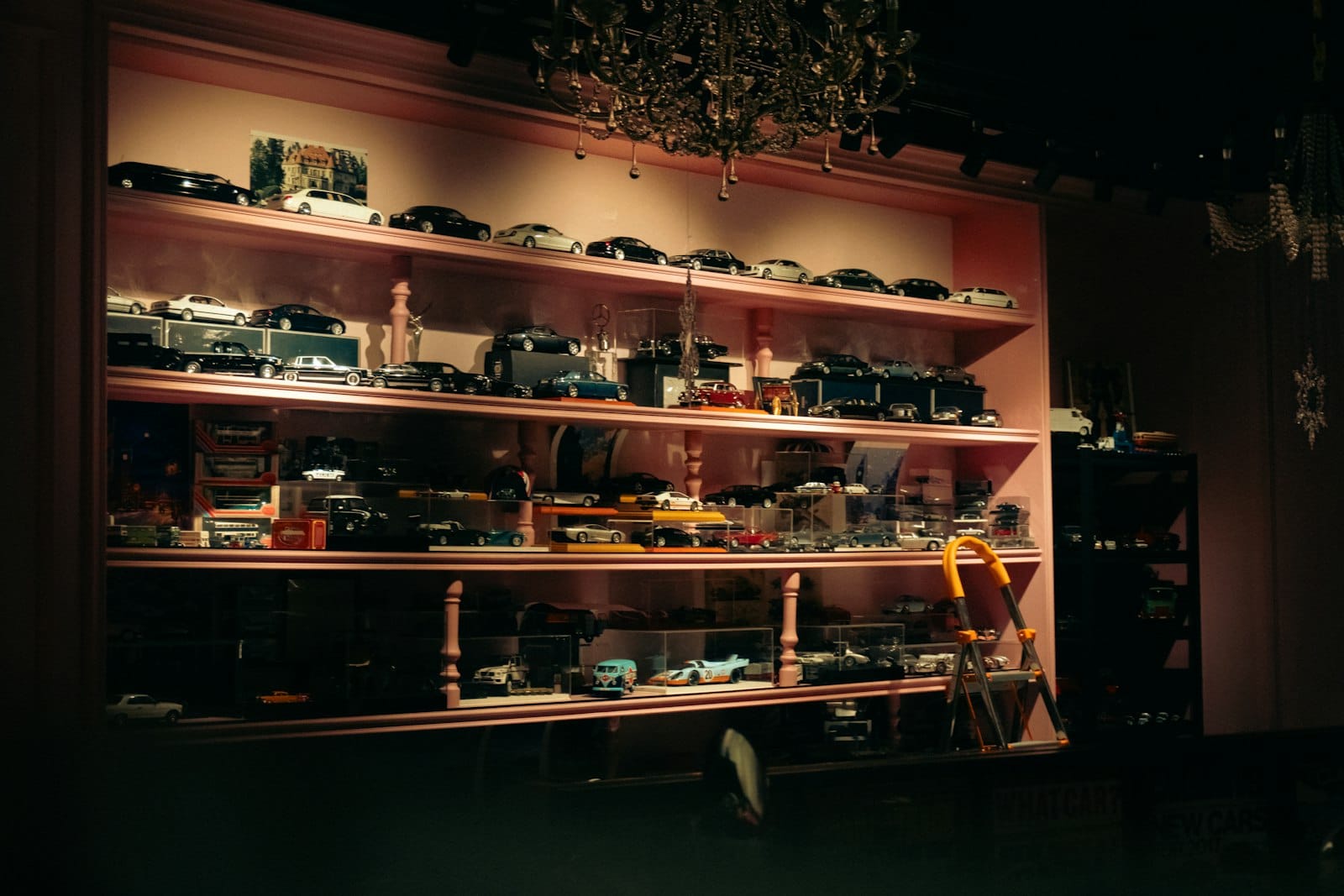 Ausstellungsregale gefüllt mit Vintage-Spielzeugautos und anderen Sammlerstücken in einem warm beleuchteten museumsartigen Interieur.