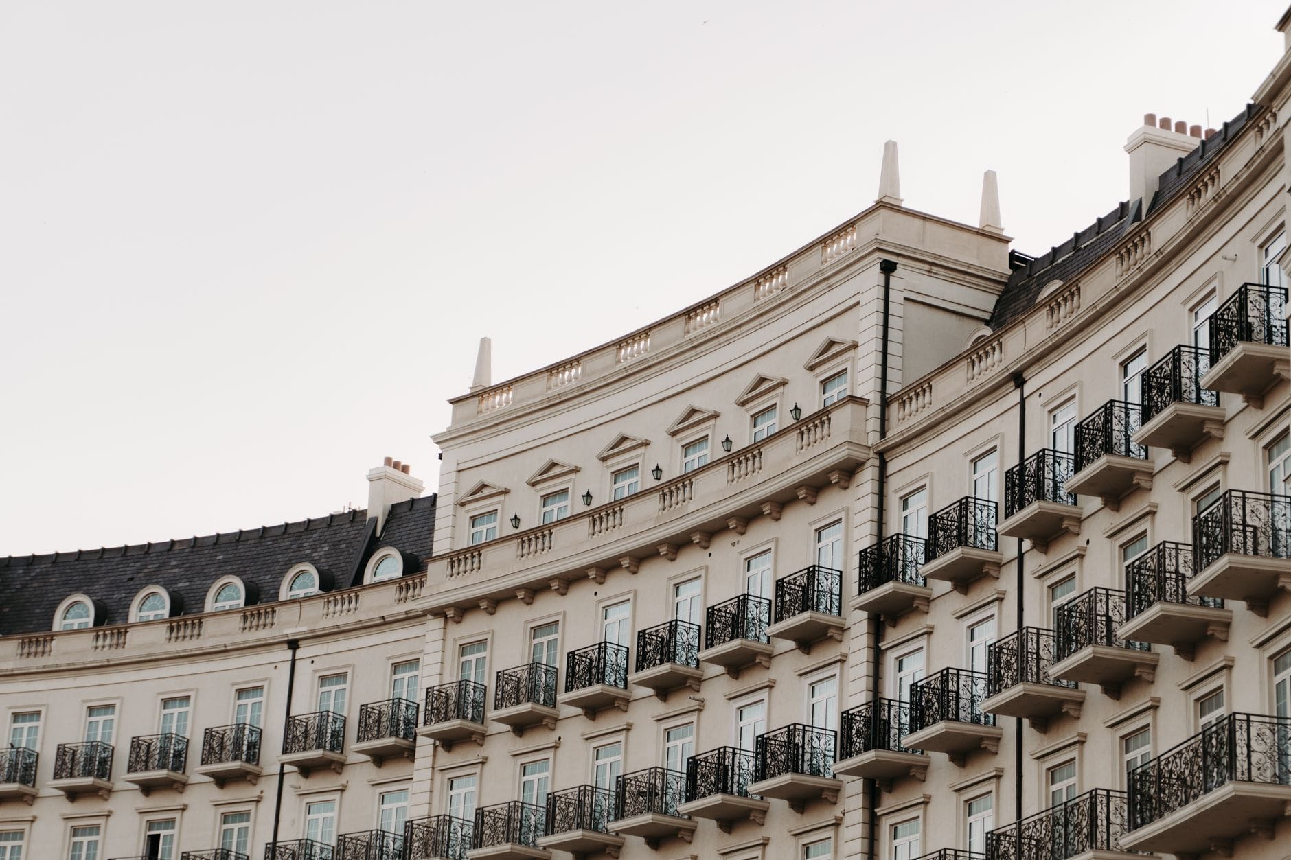 Elegante halbmondförmige Häuserzeile aus der Regency-Ära in Brighton mit weißen Stuckfassaden und verzierten Eisenbalkongeländern unter einem blassen Himmel.