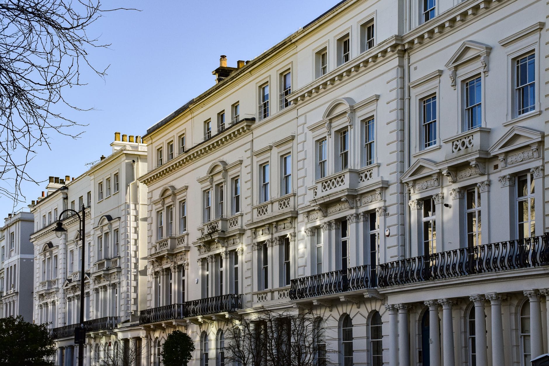 Elegante weiße Reihenhäuser im Regency-Stil in Brunswick Town mit klassischen Schmiedeeisenbalkonen und großen Schiebefenstern an einem hellen Tag.
