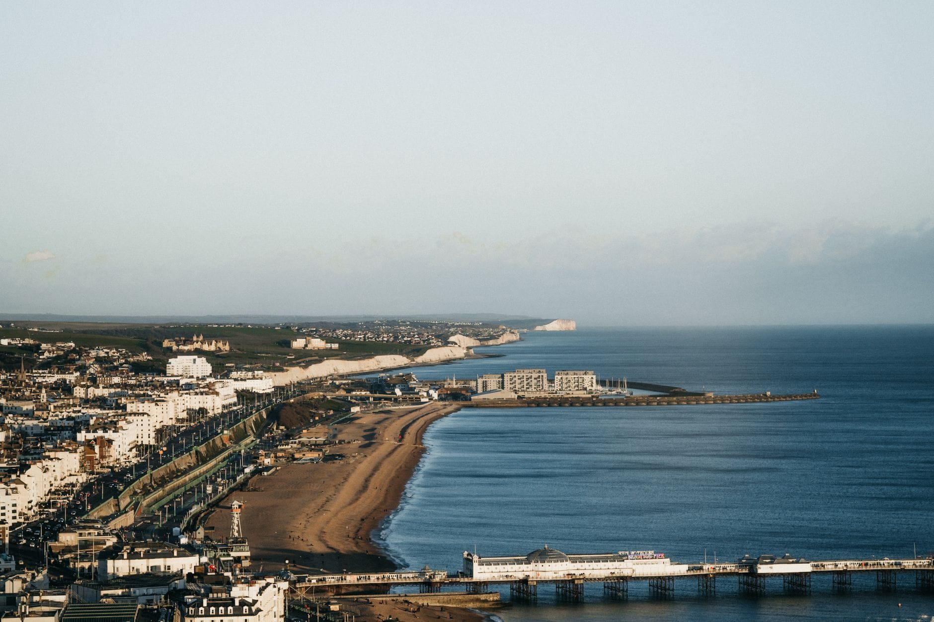 Weitläufige Luftaufnahme der Strandpromenade von Brighton mit dem Bogen der Küstenlinie, den Regency-Terrassen und Sehenswürdigkeiten entlang der Wanderroute.