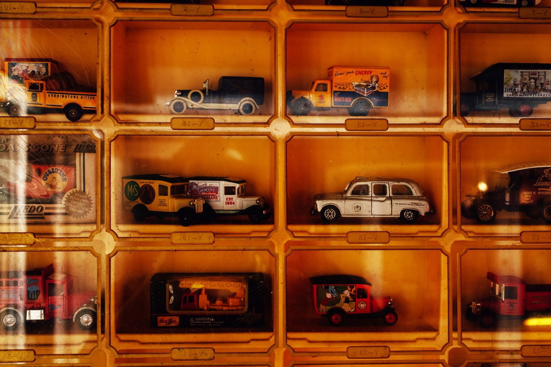 Rows of vintage toy vehicles in yellow display cases, including model cars, trucks, and vans, showcasing part of the museum's extensive collection.