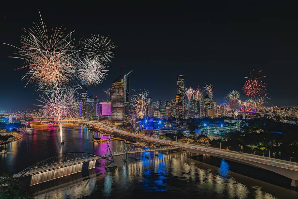 Fajerwerki rozświetlające nocne niebo nad Brisbane i rzeką Brisbane podczas festiwalu, z panoramą miasta w tle.