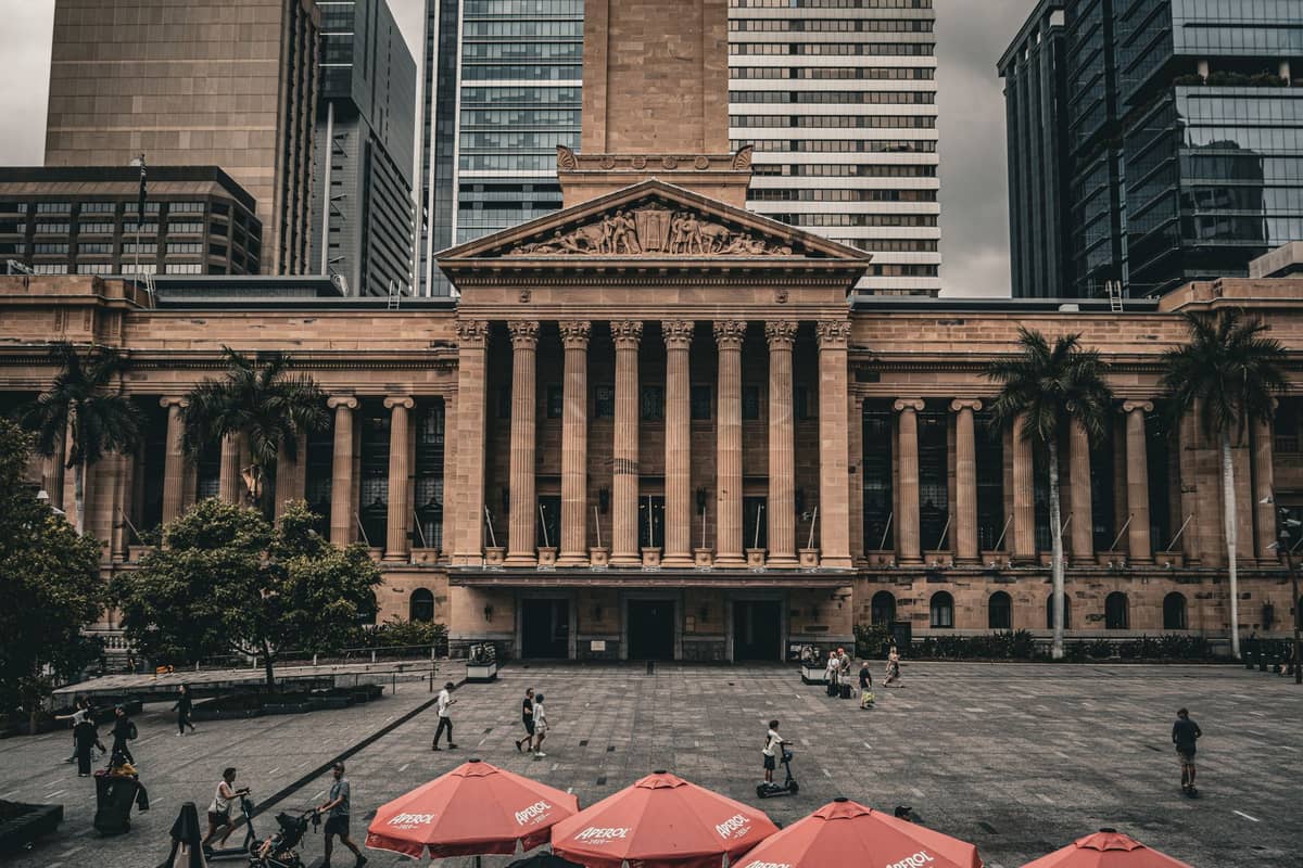 Brisbane City Hall mit seiner prachtvollen Säulenfassade, einem belebten öffentlichen Platz und modernen Bürotürmen im Hintergrund.
