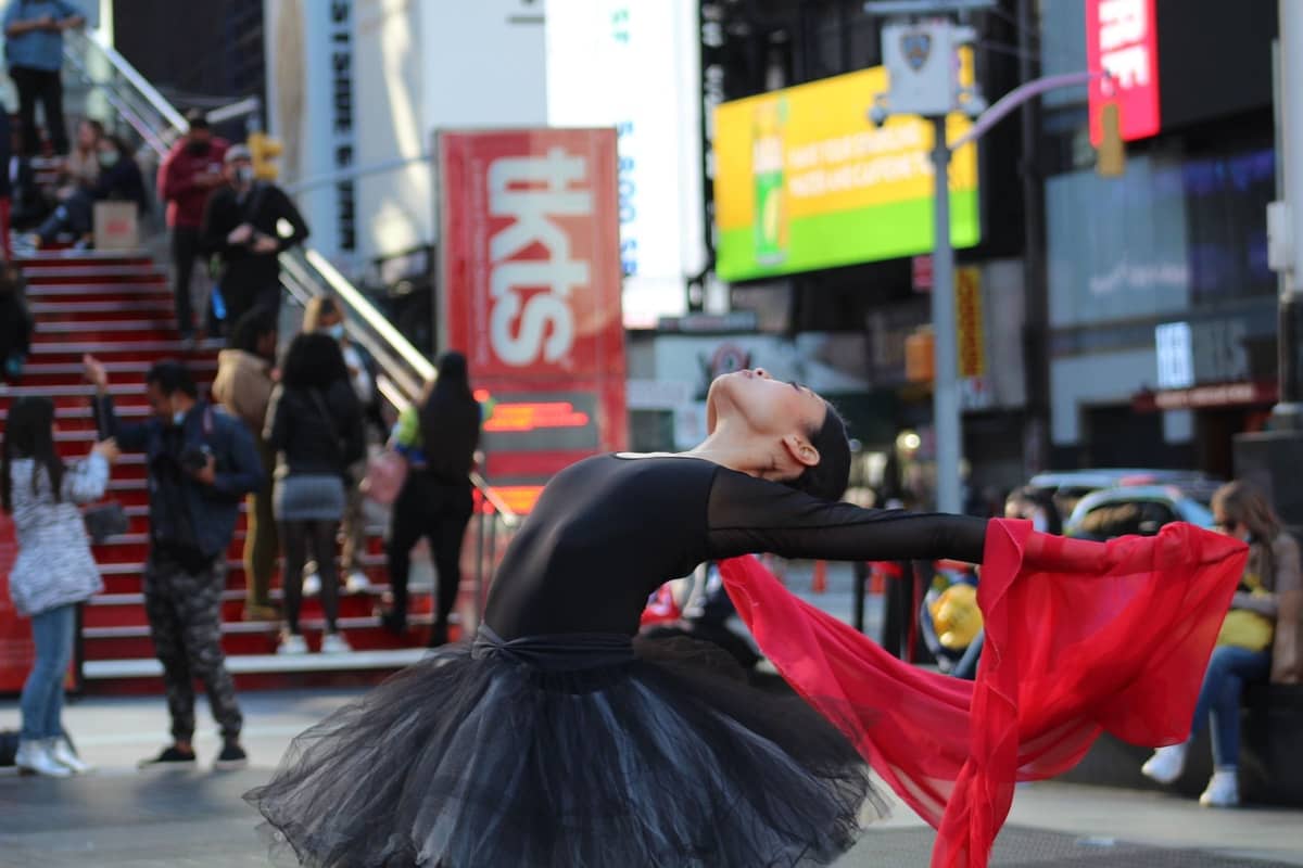Tänzer tritt am Times Square auf, mit einem sichtbaren TKTS booth-Schild im Hintergrund und Menschen in der Nähe.