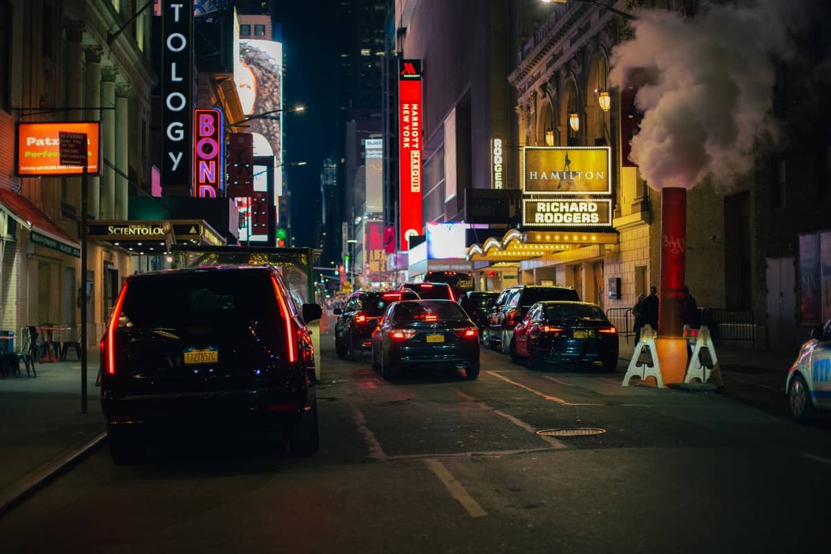 Nächtliche Straßenszene im Theater District von New York mit dem Richard Rodgers Theatre und dem Hamilton-Marquee zwischen Autos und Lichtern.