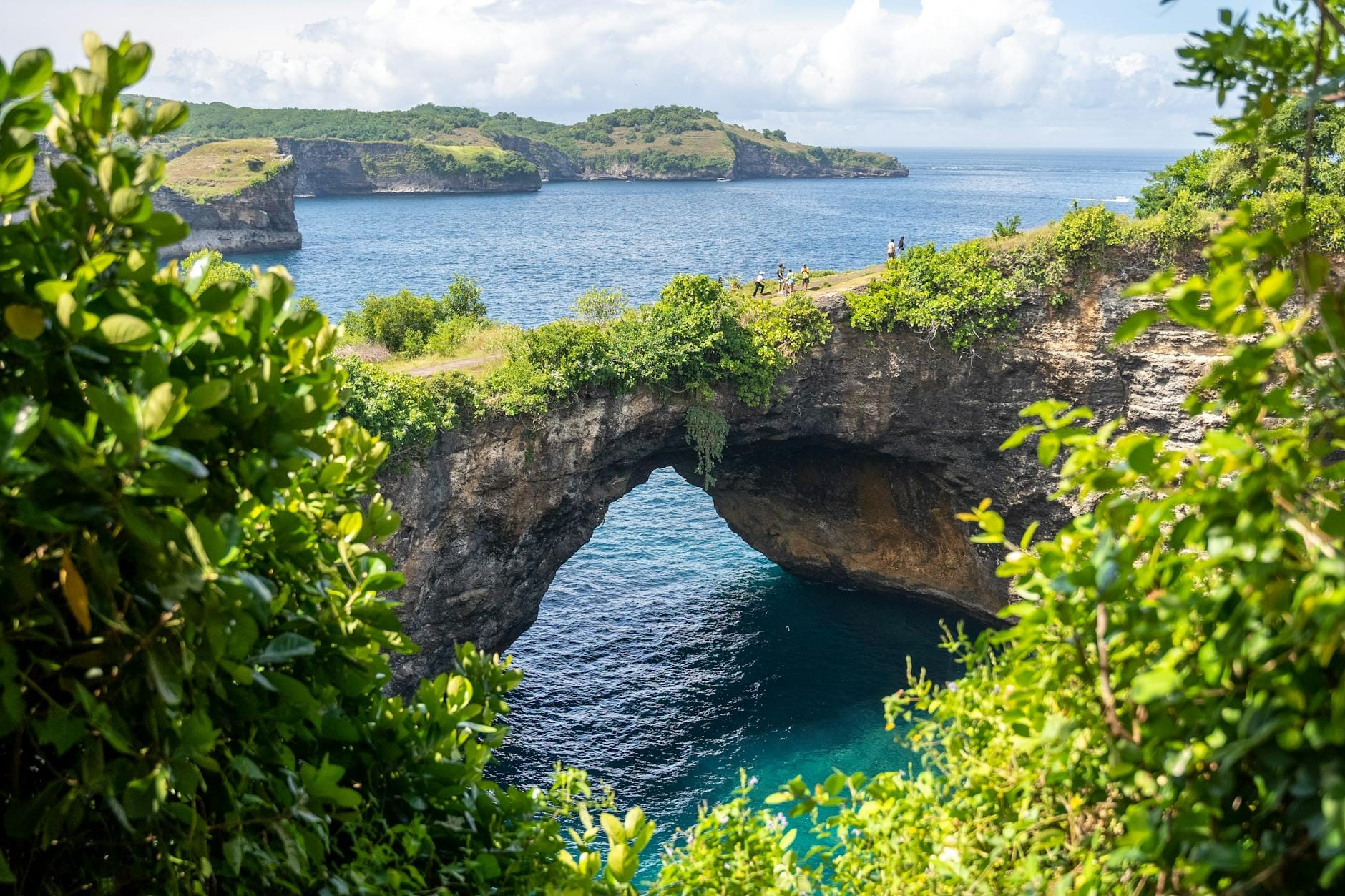 L'arco naturale di pietra e la cala circolare turchese di Broken Beach (Pasih Uug) a Nusa Penida, Bali, vista dall'alto della scogliera