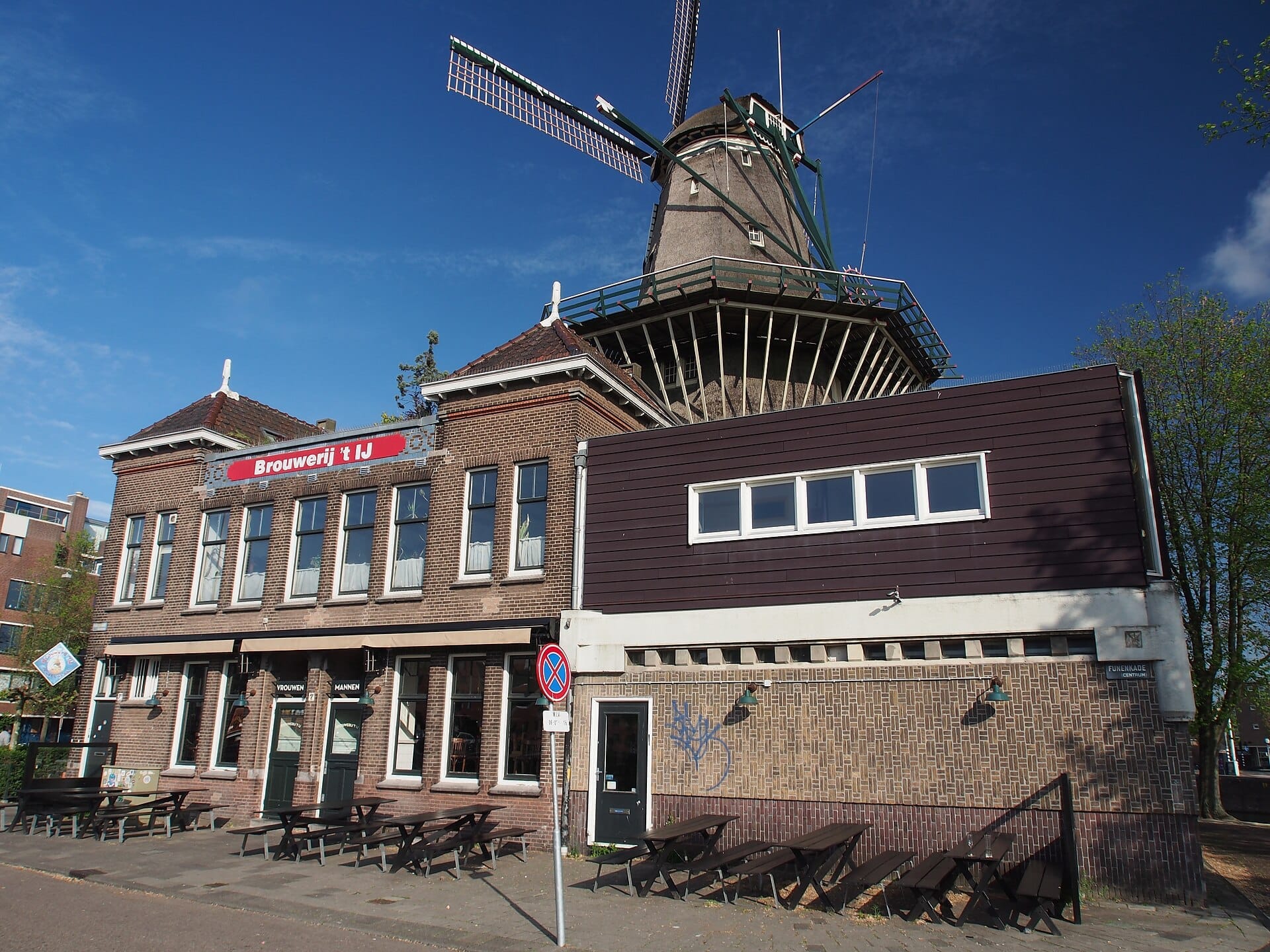 Exterior de la cervecería Brouwerij 't IJ y sala de catas con bancos al aire libre, situada bajo el histórico molino De Gooyer en Ámsterdam.