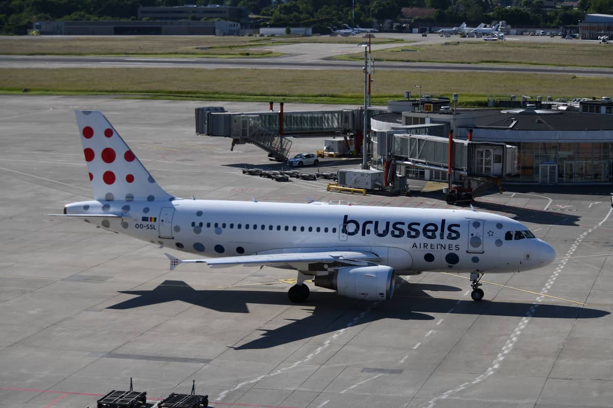 Avião da Brussels Airlines no pátio do Aeroporto de Bruxelas com os edifícios do terminal ao fundo.