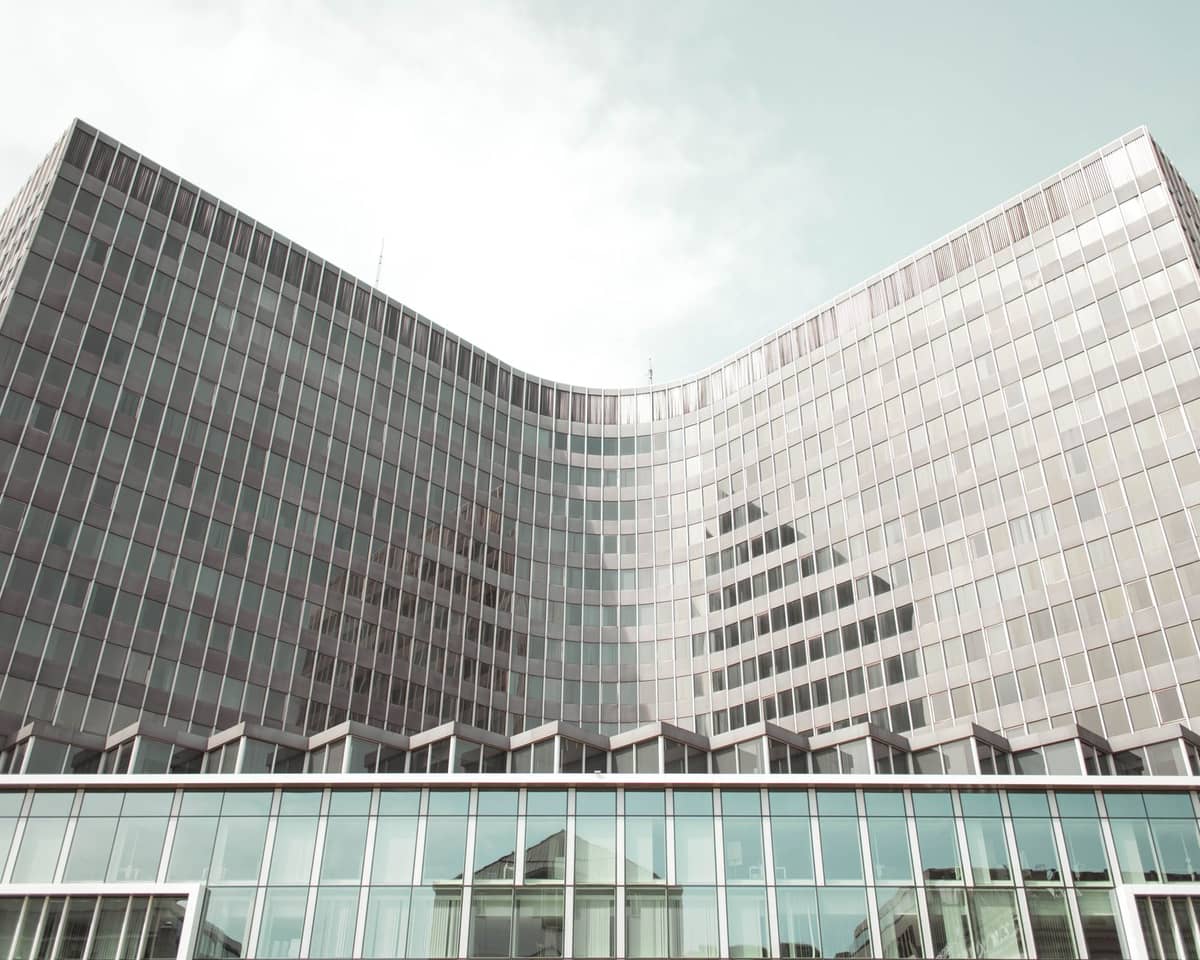 O exterior do edifício Berlaymont em Bruxelas, com a sua distintiva fachada de vidro curva e arquitetura moderna num dia de céu limpo.