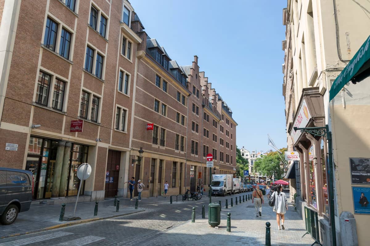 Vista em grande angular de uma rua tranquila e acolhedora de Bruxelas com vários hotéis, fachadas de tijolo e uma atmosfera urbana serena, ideal para estadias românticas.