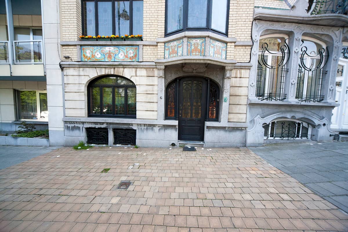Fachada de casa em fileira Art Nouveau em Bruxelas com elaborada ferragem floral, azulejos coloridos em mosaico e molduras de janela em pedra curvas