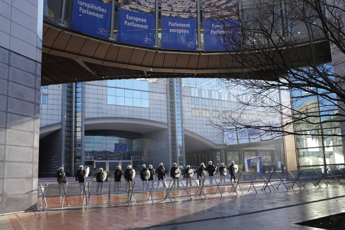 Fila de policiais com equipamento antidistúrbios atrás de barricadas em frente ao edifício do Parlamento Europeu em Bruxelas.