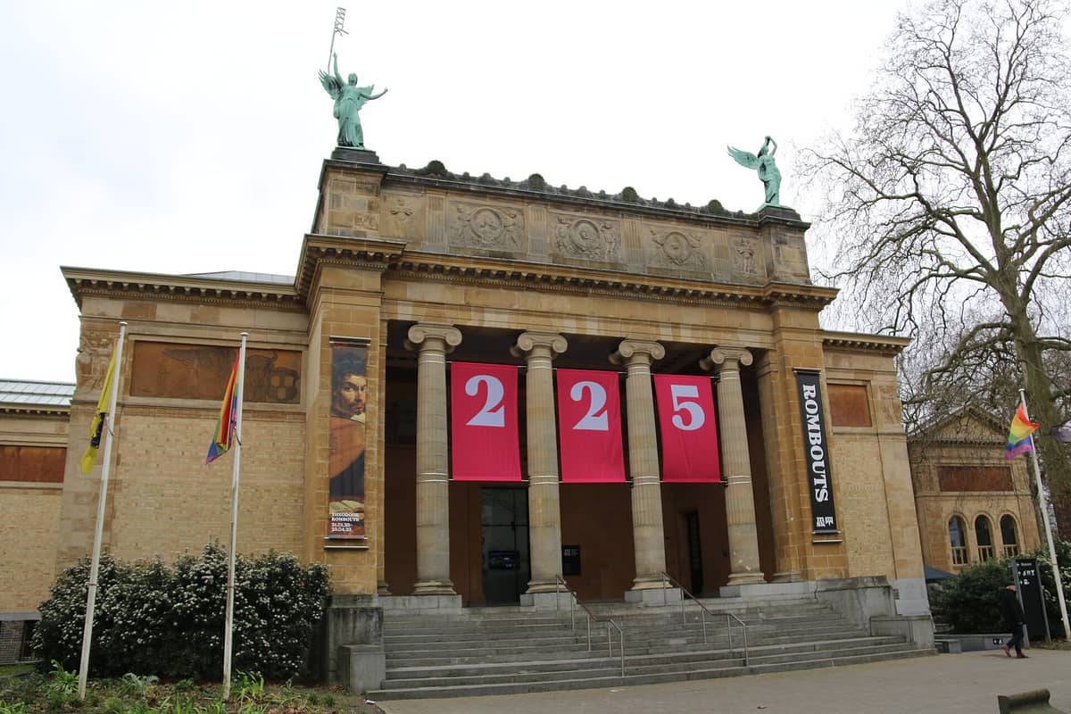 Exterior of Museum of Fine Arts Ghent (MSK), showing neoclassical columns, statues, banners, and steps at the entrance.