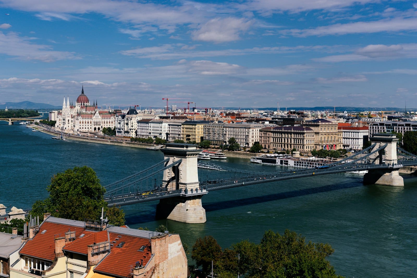 Tagesansicht von Budapest mit der Kettenbrücke und dem Parlamentsgebäude entlang der Donau, mit prächtigen Gebäuden und klarem Himmel.