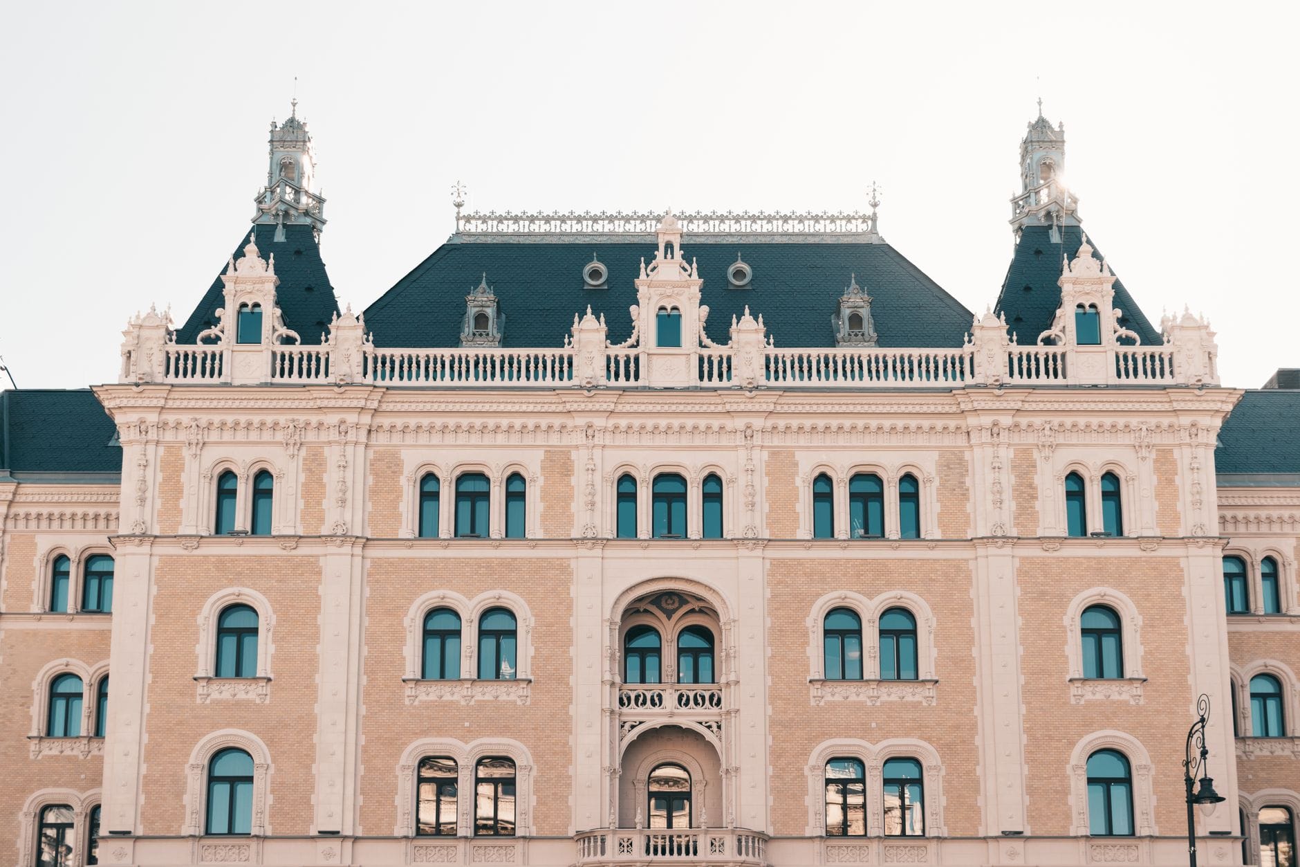 Elegantes historisches Gebäude mit verzierter Architektur und mehreren Bogenfenstern, bei hellem Tageslicht aufgenommen, geeignet für einen Luxushotelbeitrag in Budapest.